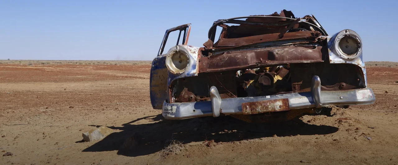 Rusted old junk car sitting in an open field